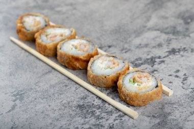 Sıcak kızarmış suşi ruloları ve taş masada tek kullanımlık tahta çubuklar. Yüksek kalite fotoğraf