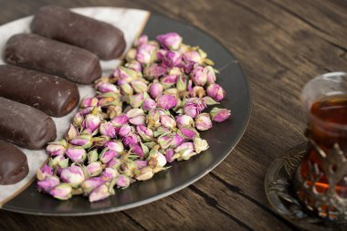 Bir bardak siyah çayın yanında çikolata çubukları ve gül çiçekleri olan bir tabak. Yüksek kalite fotoğraf