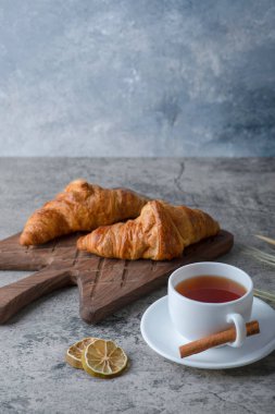 Tahta kesme tahtası, taze kruvasan ve bir fincan sıcak çay. Yüksek kalite fotoğraf