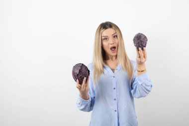 Mavi elbiseli güzel bir kadın beyaz arka planda mor lahana tutuyor. Yüksek kalite fotoğraf