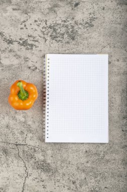 Turuncu taze dolmalık biber ve taş yüzeyde boş defter. Yüksek kalite fotoğraf