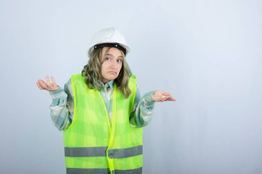 Beyaz fonda duran beyaz şapkalı genç inşaat işçisinin görüntüsü. Yüksek kalite fotoğraf