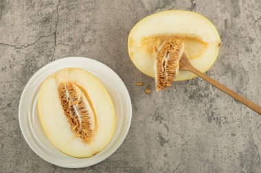 Beyaz tabakta, ahşap kaşıkla yarım lezzetli sarı kavun. Yüksek kalite fotoğraf