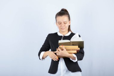 Beyaz arka planda duran kitapları olan genç bir kız öğrencinin portresi. Yüksek kalite fotoğraf