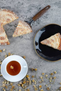 Lezzetli bir parça kek ve beyaz bir fincan sıcak çay ile siyah bir tabak. Yüksek kalite fotoğraf