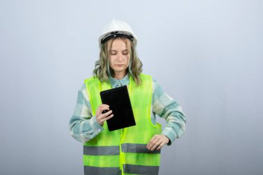 Not defteriyle beyaz duvarda poz veren güzel bir kadın mühendis resmi. Yüksek kalite fotoğraf