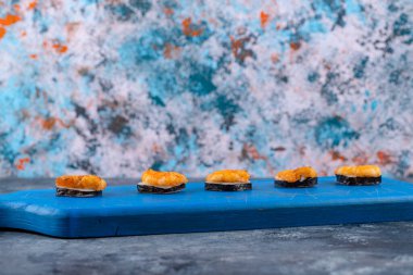 Tahta kesme tahtasına yerleştirilmiş karidesli taze lezzetli suşi ruloları. Yüksek kalite fotoğraf