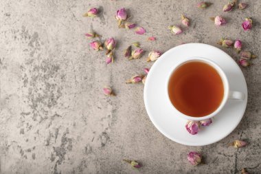 Taş yüzeyinde kurumuş güller olan bir fincan siyah sıcak çay. Yüksek kalite fotoğraf