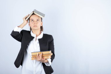 Kafasında bir sürü kitap olan güzel bir öğretmenin resmi. Yüksek kalite fotoğraf