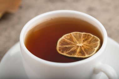 White cup of black tea with lemon slice on stone background. High quality photo