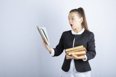 Beyaz arka plan üzerine kitap okuyan bir kız öğrencinin resmi. Yüksek kalite fotoğraf