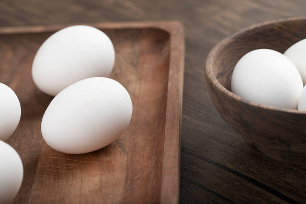 Organic eggs. White eggs in wooden tray and inside of bowl. High quality photo