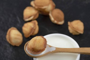 Siyah arka planda kaşık ve ceviz kurabiyeli bir fincan süt. Yüksek kalite fotoğraf