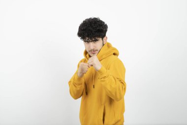 Sarı kapüşonlu, poz veren esmer bir adamın fotoğrafı. 