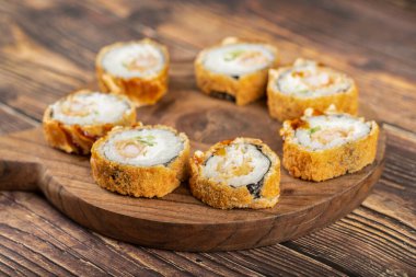 Tahta kesme tahtasına yerleştirilmiş füme tavuk göğsünden yapılmış taze suşi ruloları. Yüksek kalite fotoğraf