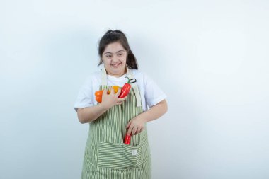 Kareli önlüğün içinde duran ve cebine sebze koyan genç ve güzel bir kız. Yüksek kalite fotoğraf