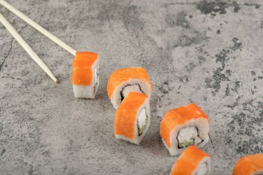 Taş yüzeyine geleneksel Philadelphia suşi ruloları konur. Yüksek kalite fotoğraf