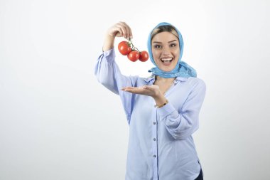 Mavi şallı, kırmızı domatesli genç bir kadının fotoğrafı. Yüksek kalite fotoğraf