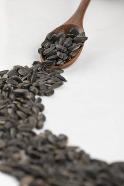 Beyaz arka planda siyah ayçiçeği tohumlarıyla dolu tahta kaşık. Yüksek kalite fotoğraf