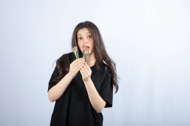 Makyajlı, beyaz arka planda fırçaları olan genç ve güzel bir model. Yüksek kalite fotoğraf