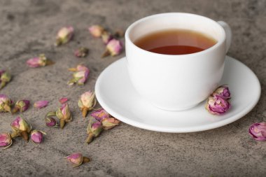 Cup of black hot tea with dried roses on stone surface. High quality photo
