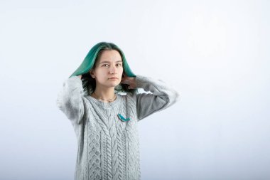 Beyaz arka planda kameraya poz veren yeşil saçlı kızın portresi. Yüksek kalite fotoğraf