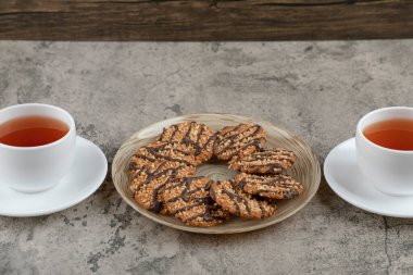 Susamlı kurabiyeler ve mermer yüzeyde iki fincan çay. Yüksek kalite fotoğraf