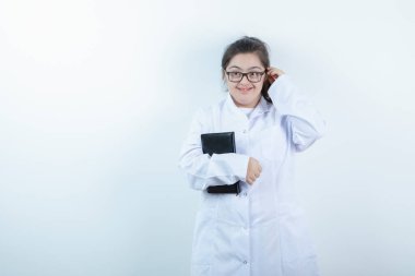 Doktor üniformalı genç bir kız ayakta ve elinde not defteri var. Yüksek kalite fotoğraf