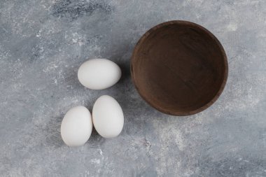 Mermer arka planda taze beyaz tavuk yumurtası dolu ahşap bir kase. Yüksek kalite fotoğraf
