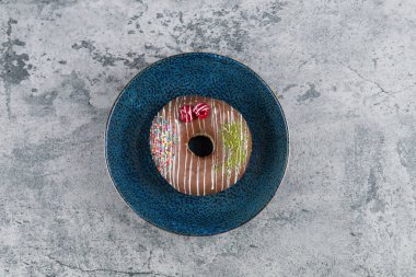 Çilekli çikolatalı donut ve mermer yüzeyine serpiştirilmiş mavi tabak. Yüksek kalite fotoğraf