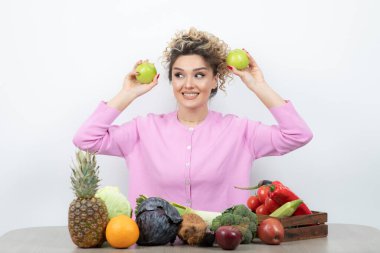 Güzel ev hanımının elinde taze elmalarla masada oturduğu bir fotoğraf. Yüksek kalite fotoğraf