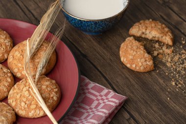 Tohumlu çatlamış yulaf ezmeli bisküviler ve ahşap masada bir kase taze süt. Yüksek kalite fotoğraf