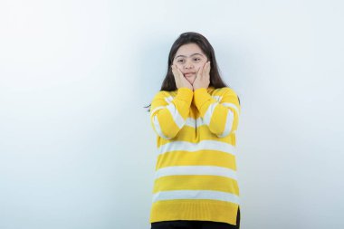 Beyaz duvarın üzerinde duran ve poz veren Down sendromlu şirin bir çocuk portresi. Yüksek kalite fotoğraf