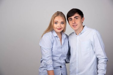 Genç çift ayakta durup gri duvara doğru kameraya bakıyor. Yüksek kalite fotoğraf