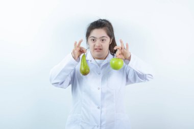 Doktor üniformalı genç bir kız elinde yeşil elmalı armut meyvesi tutuyor. Yüksek kalite fotoğraf