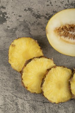 Taş zeminde sulu olgun ananas dilimleri ve sarı kavun. Yüksek kalite fotoğraf