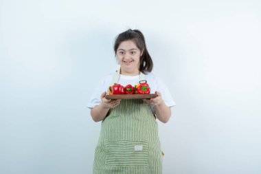 Önlüklü genç bir kız taze sebzeli ahşap bir tahta taşıyor. Yüksek kalite fotoğraf