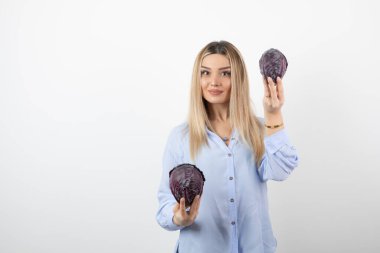 Mavi elbiseli güzel bir kadın beyaz arka planda mor lahana tutuyor. Yüksek kalite fotoğraf