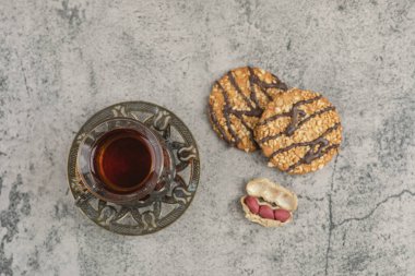 Bir bardak siyah çay, lezzetli bisküviler, çikolata ve mermer yüzeyde tohumlar. Yüksek kalite fotoğraf