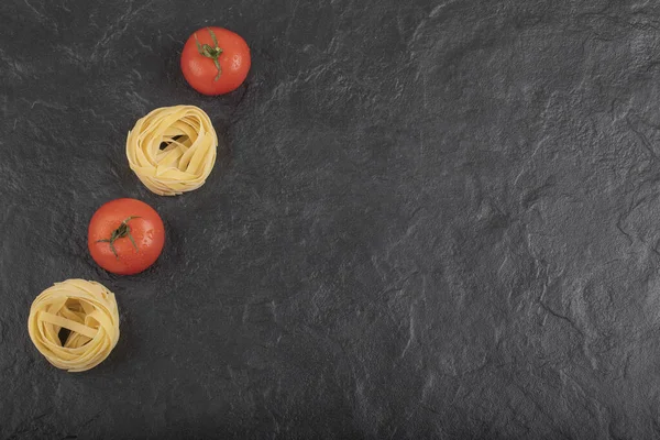 Rohe Tagliatelle Nester Mit Frischen Tomaten Auf Schwarzer Oberfläche Hochwertiges — Stockfoto