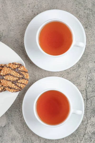Üzerine tohum serpiştirilmiş taze yulaf ezmeli kurabiyeler ve iki fincan siyah çay. Yüksek kalite fotoğraf