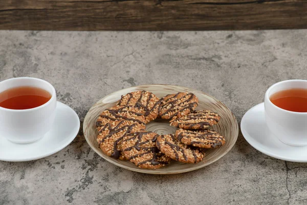 Susamlı kurabiyeler ve mermer yüzeyde iki fincan çay. Yüksek kalite fotoğraf