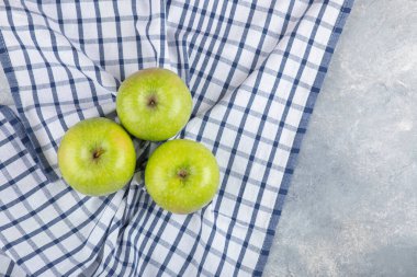 Taş zeminde masa örtüsü olan üç sağlıklı yeşil elma. Yüksek kalite fotoğraf