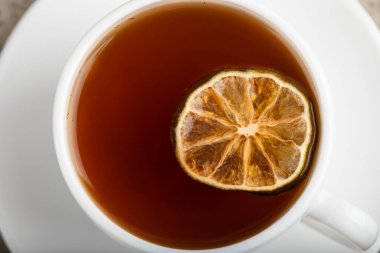 White cup of black tea with lemon slice on stone background. High quality photo