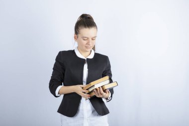 Beyaz arka planda bir sürü kitapla poz veren genç bir kızın portresi. Yüksek kalite fotoğraf