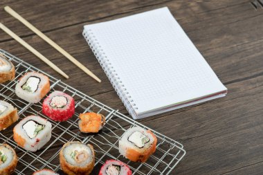 Ahşap zemin üzerinde çubuklar olan çeşitli suşi ruloları. Yüksek kalite fotoğraf