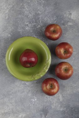 Mermer yüzeyinde tek kırmızı elma olan yeşil kase. Yüksek kalite fotoğraf