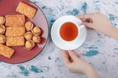  Dişi eller, bir fincan çayla fındık ekmeği ve konsantre süt tutuyor. Yüksek kalite fotoğraf