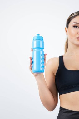 Mavi su şişesi tutan genç atletik kadının yarım pozu. Yüksek kalite fotoğraf