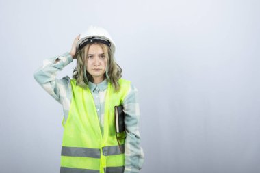 Not defteriyle beyaz duvarda poz veren güzel bir kadın mühendis resmi. Yüksek kalite fotoğraf